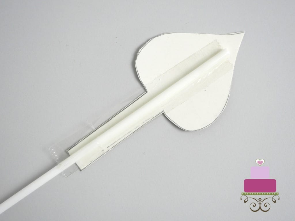The back of a paper arrow with a white pick attached with tape
