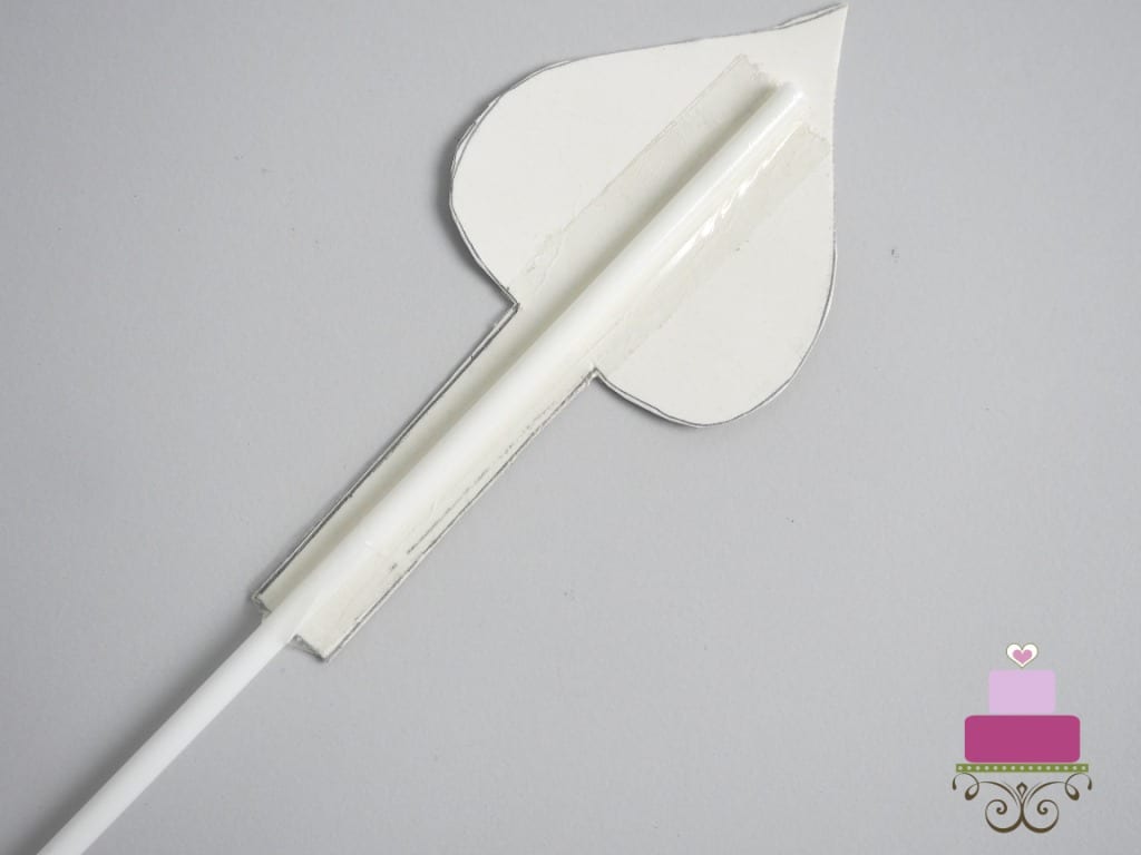 The back of a paper arrow with a white pick attached with tape