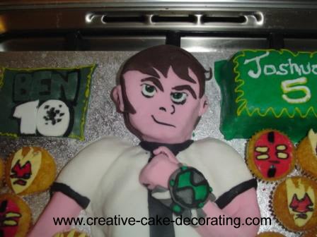 Ben 10 shaped 2D cake with cupcakes on the side