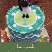 A round cake with a sheep cake topper.