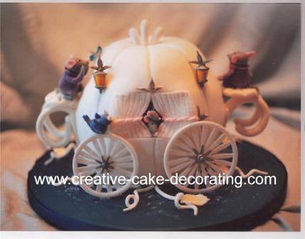 White carriage shaped cake with Cinderella figurine on the side.