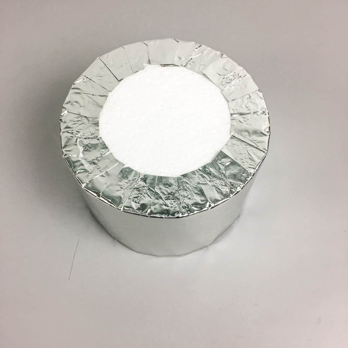 A round styrofoam block wrapped in silver paper.