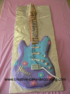 An electric guitar shaped 2d cake decorated in purple and blue