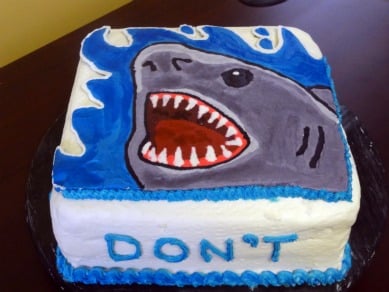 A square cake with a shark jaws image on top.