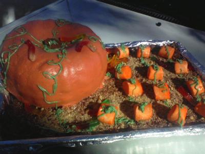 A rectangle cake with a pumpkin shaped cake on top and smaller pumpkin toppers on the remaining top space of the cake