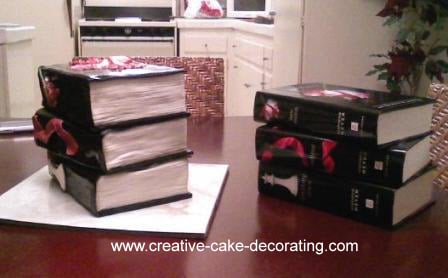 A stack of 3 books cake with black cover and white pages.