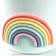 Fondant rainbow on the side of a light blue fondant covered cake.