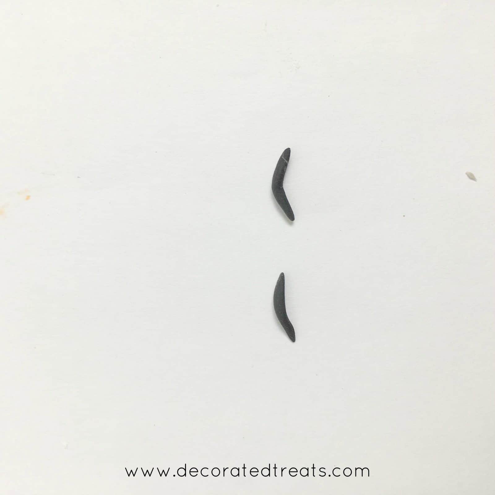 Tiny black fondant brows on a piece of white paper