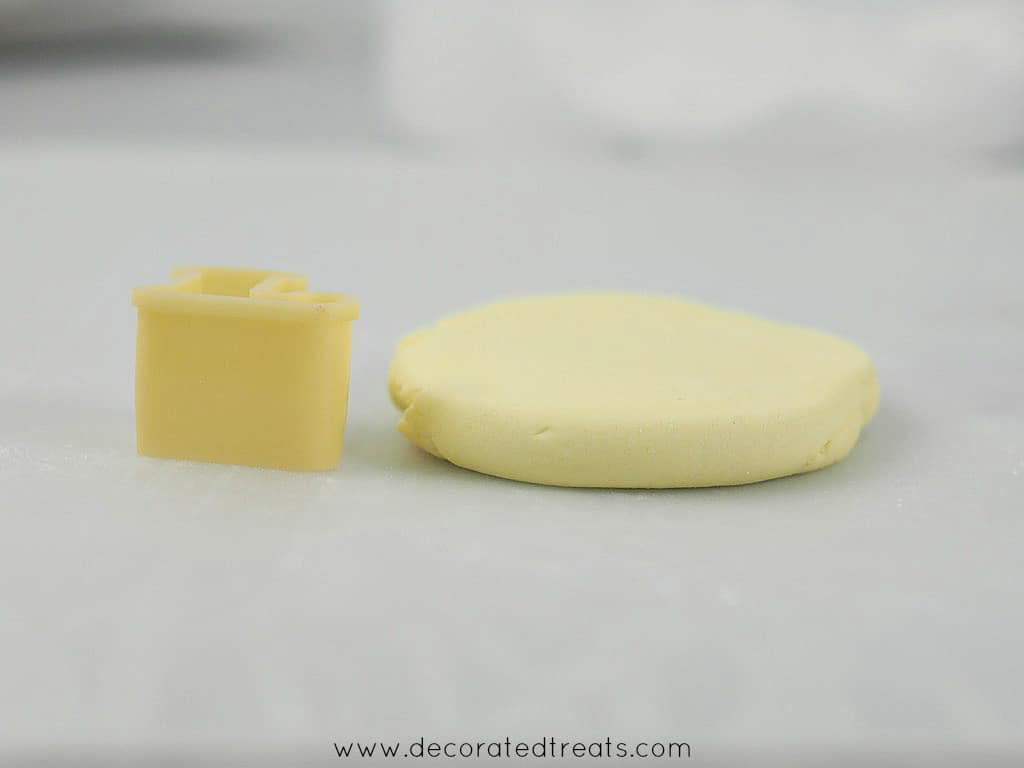 A piece of rolled fondant with a letter L cutter at the side
