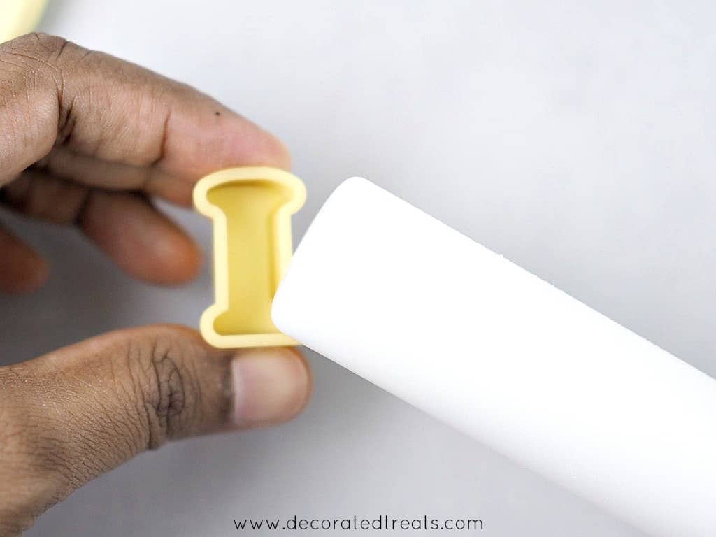 Using a small rolling pin to knock out fondant from an alphabet cutter