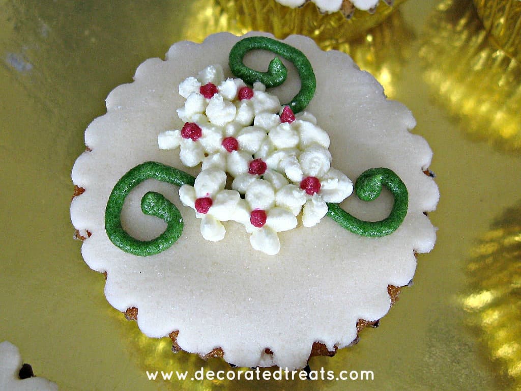 A cupcake with white piped flowers and green swirls