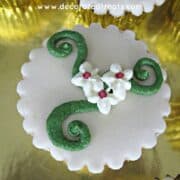 A cupcake with white piped flowers and green swirls.