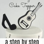 A black and white 3D fondant guitar cake topper on a cake.