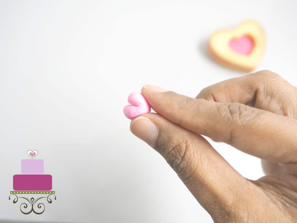 Holding small pink fondant heart in hand