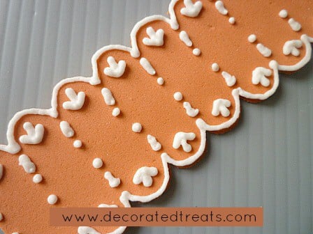 A strip of orange fondant with royal icing lace piping