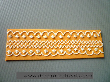 A strip of amber fondant with royal icing lace piping