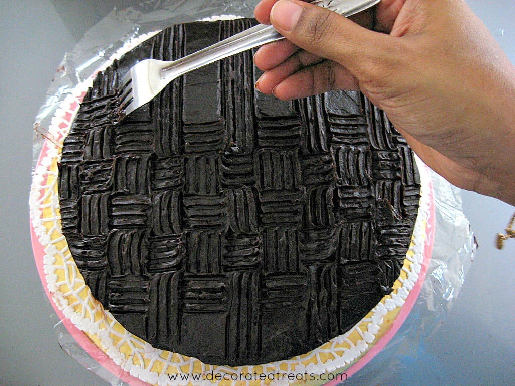 Using a fork to create basket weave pattern on a chocolate covered cake