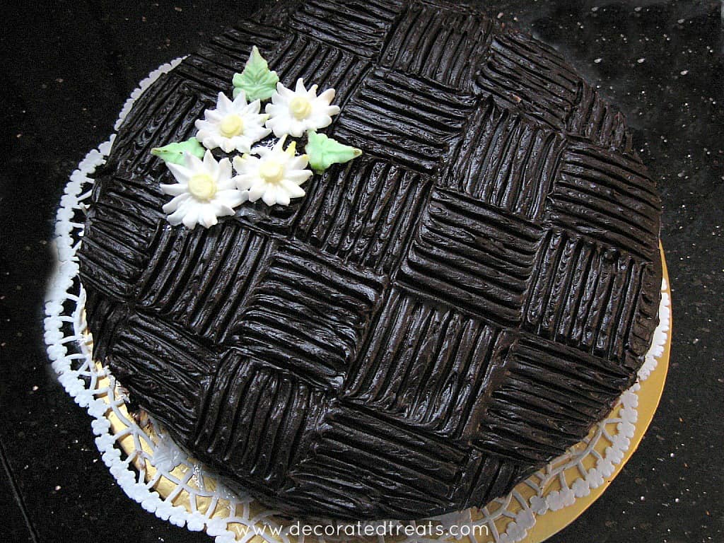 Chocolate cake with wide basket weave pattern and white royal icing daisies