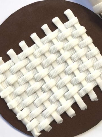 Basket weave buttercream pattern in white against brown background.