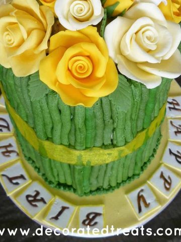 A tall cake with yellow and white roses and green sides.