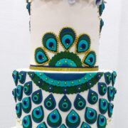 A peacock inspired tiered cake decorated with gold dragees.