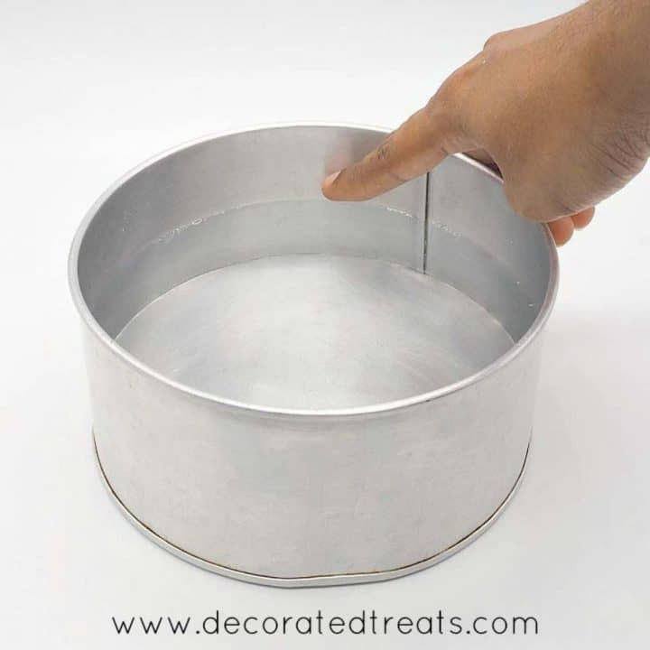 Pointing to the water level in a cake tin filled with water