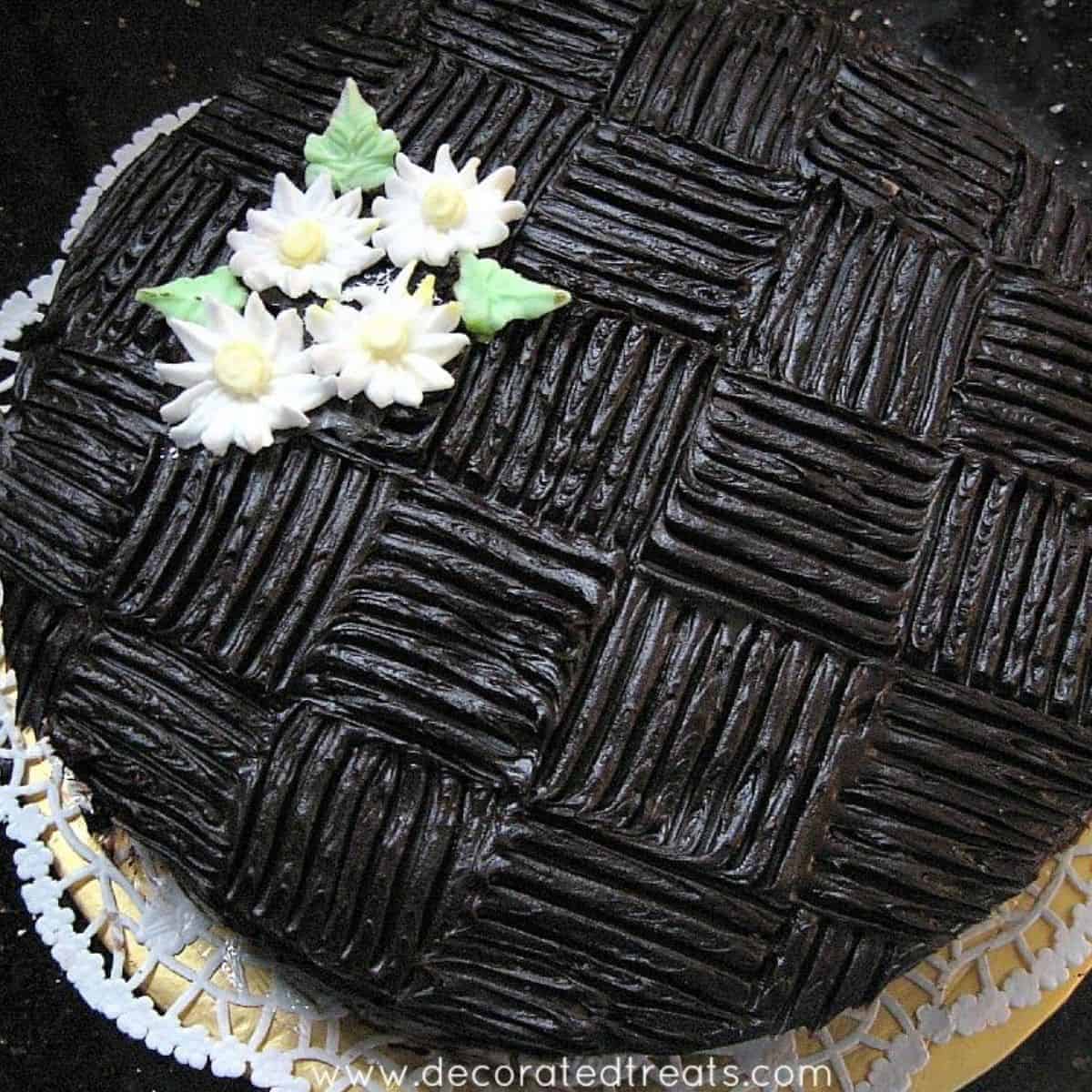 Chocolate cake with wide basket weave pattern and white royal icing daisies