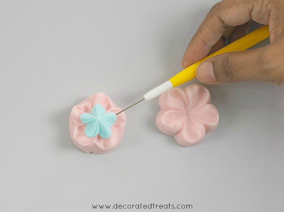 Using a needle tool to remove fondant flower from silicone mold.