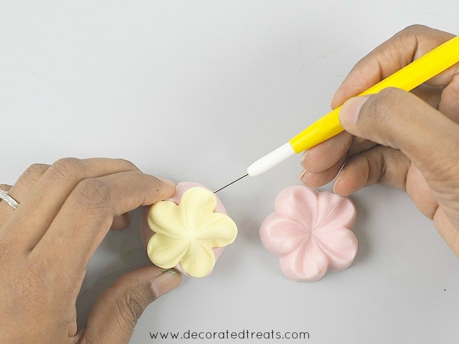 Using a needle tool to remove fondant flower from silicone mold.