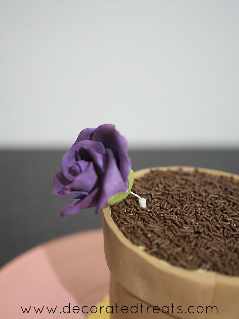 A purple gum paste flower in a flower pot cake