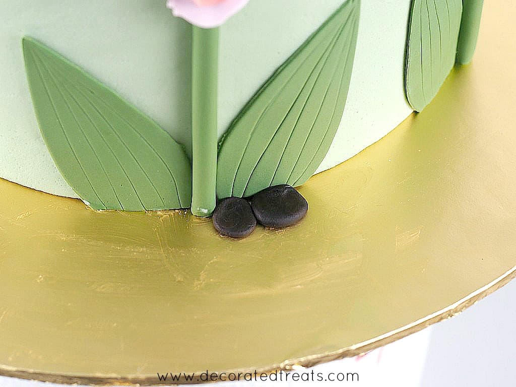 2 small pieces of flat, brown fondant on a gold cake board