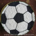 A round cake with the top decorated in a black and white football.