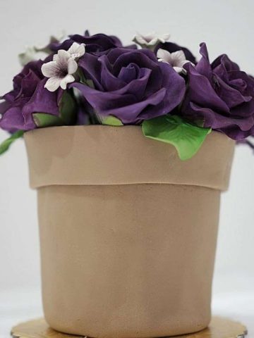 A flower pot cake with purple gum paste roses.