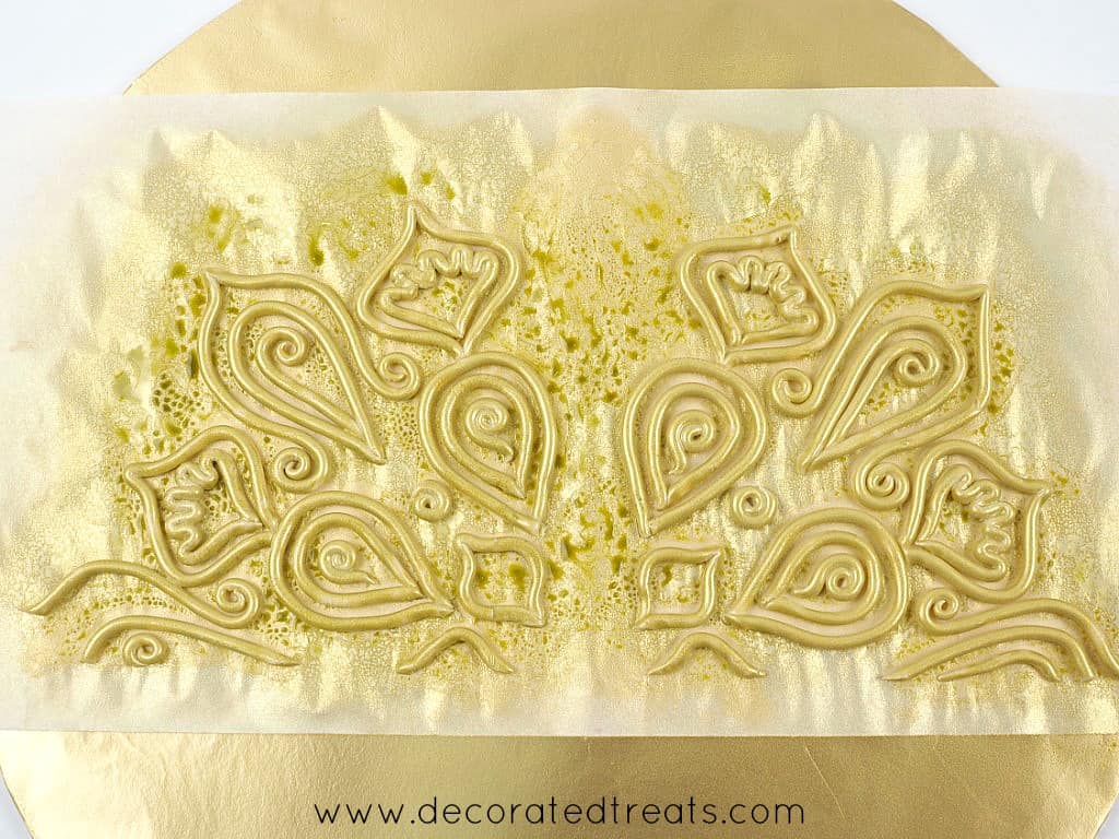 Gold fondant lace on a paper template.