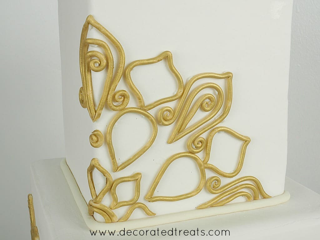 Gold fondant lace on a square cake.