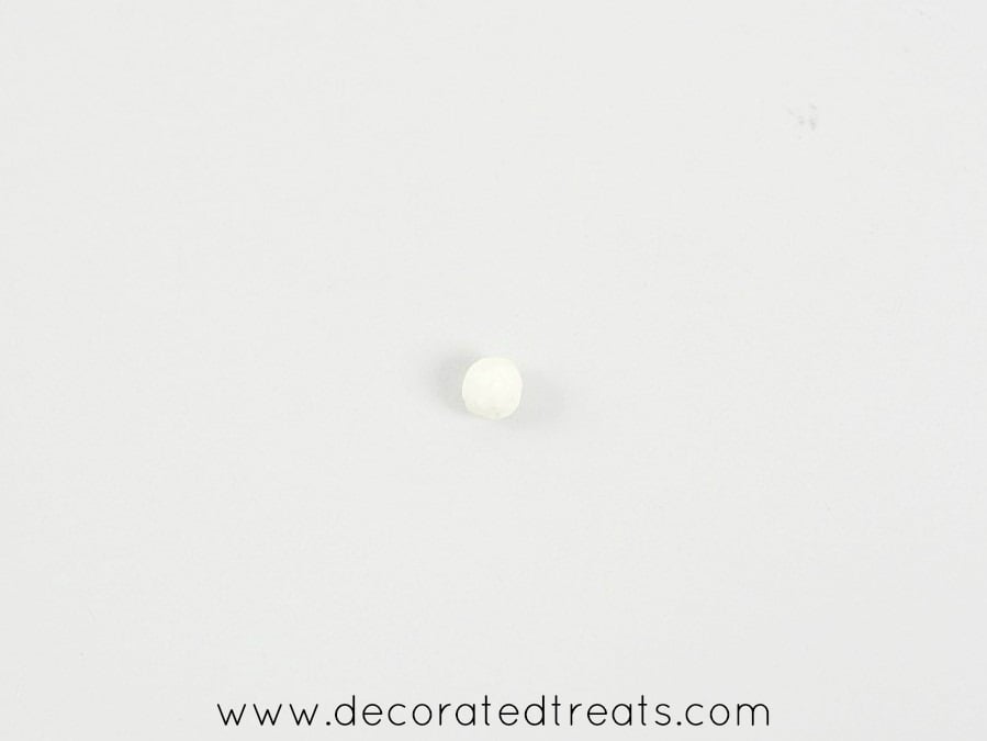 A tiny round white gum paste ball