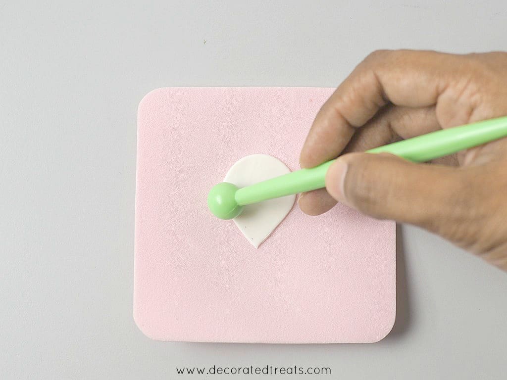 Using a green ball tool to thin the petals of a gum paste piece