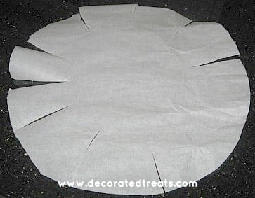 A round piece of parchment paper with the sides cut at equal intervals
