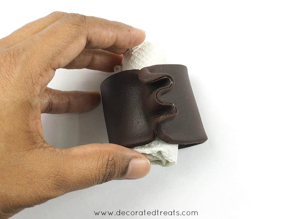 A strip of brown fondant wrapped around a small roll of tissue and the edges gathered.