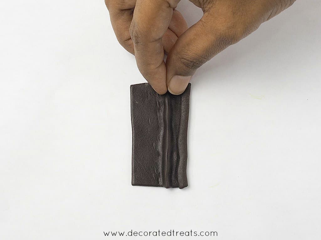 Pinching the center of a brown fondant cut out.