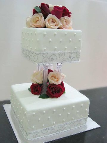 A 2 tier cake stacked on pillars