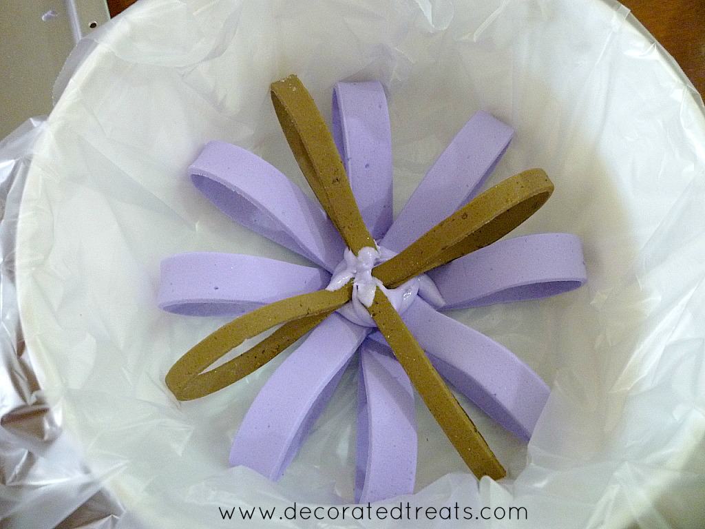 A round row of brown and violet fondant loops in a plastic lined white container
