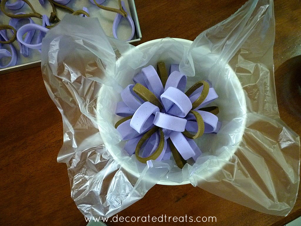A round row of brown and violet fondant loops in a plastic lined white container