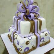 A 2 tier square cake decorated with fondant loop bow in violet and brown.