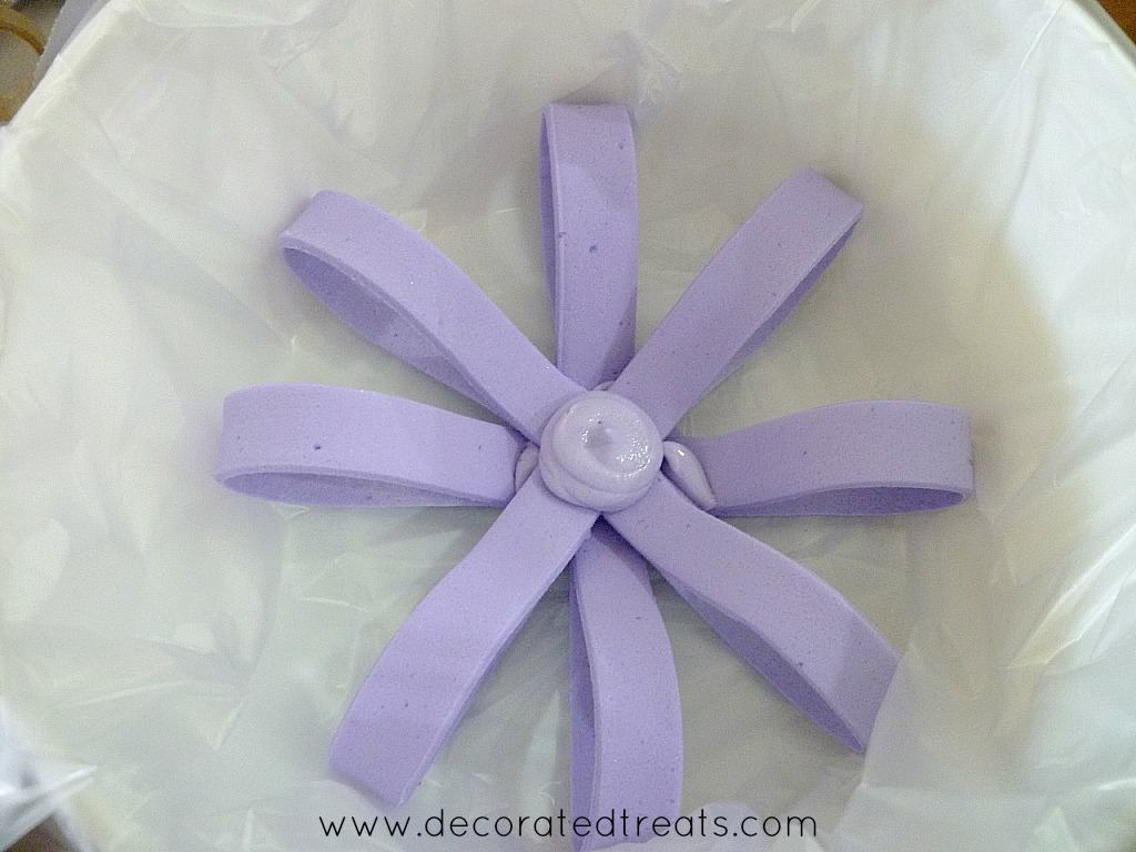 A round round of violet fondant loops in a plastic lined white container