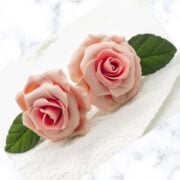 2 pink gum paste roses against a marble background.