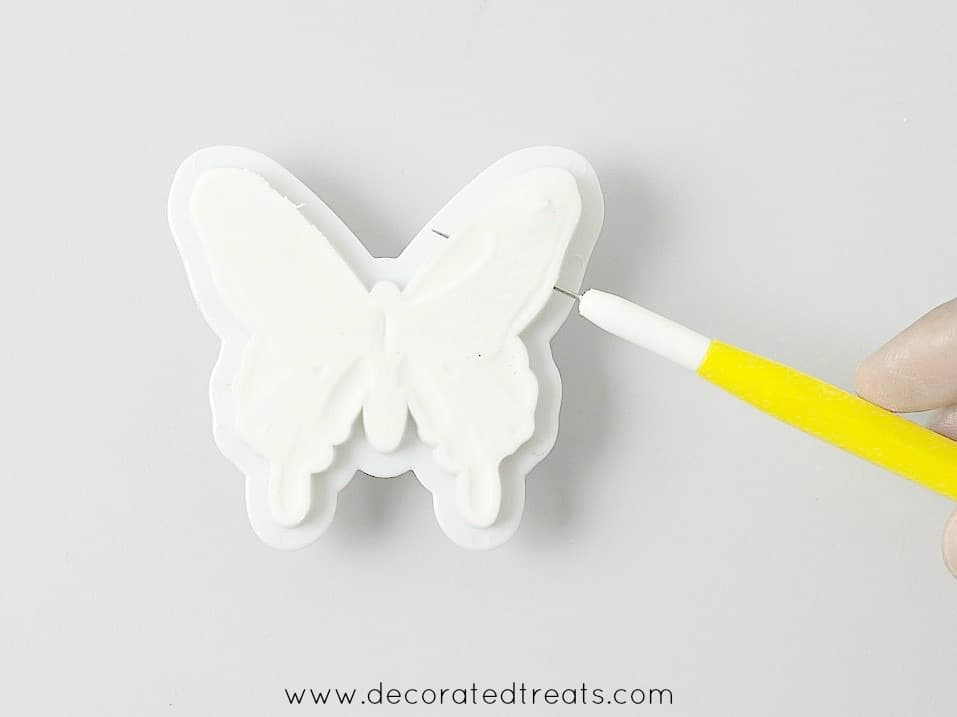 Using a needle tool to remove gum paste butterfly from its cutter