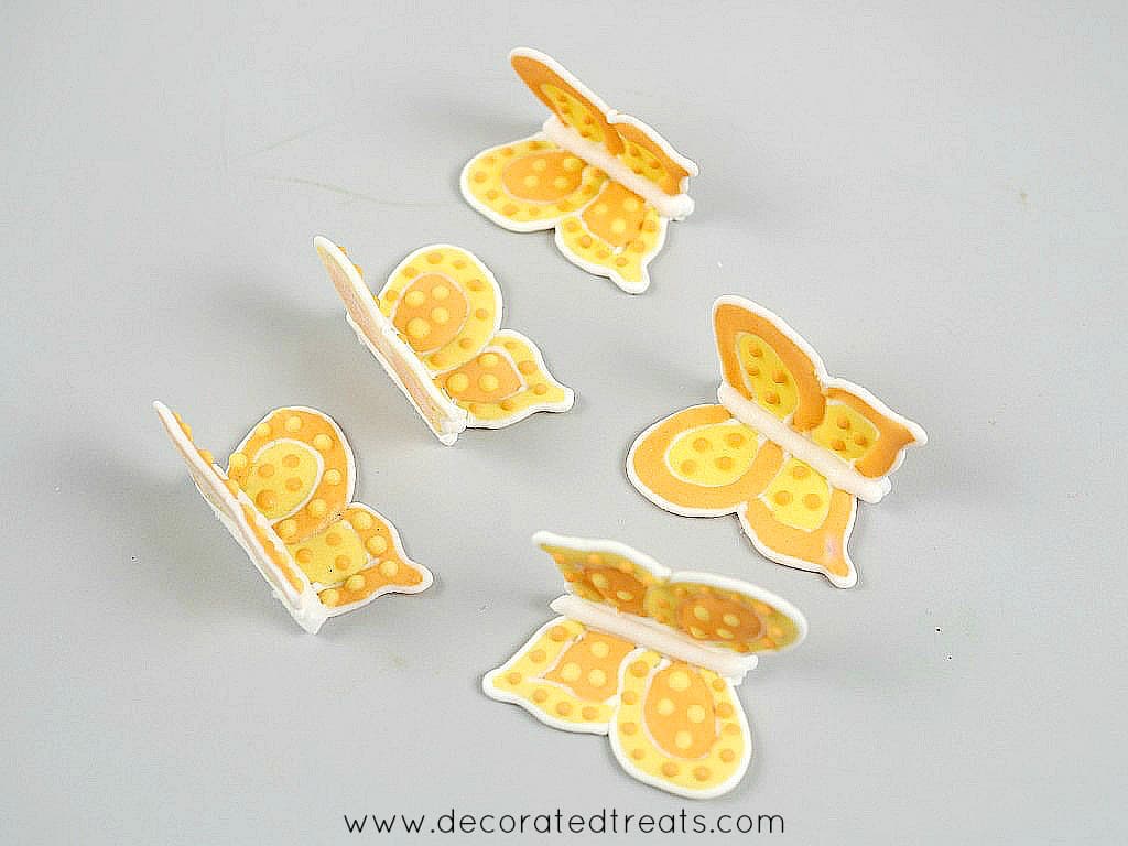Orange and yellow royal icing butterflies against a grey background.