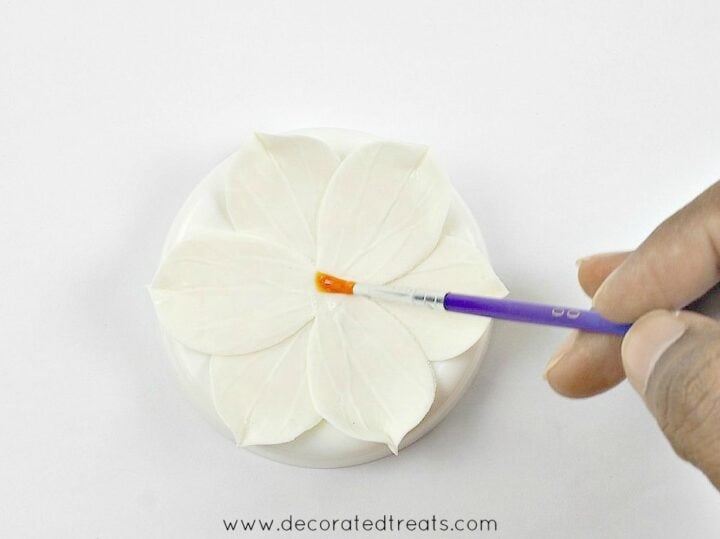 Using a purple brush to apply glue to the center of a gum paste flower.