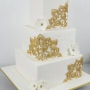 A 3 tier square cake in white, with gold lace and white gum paste flowers.